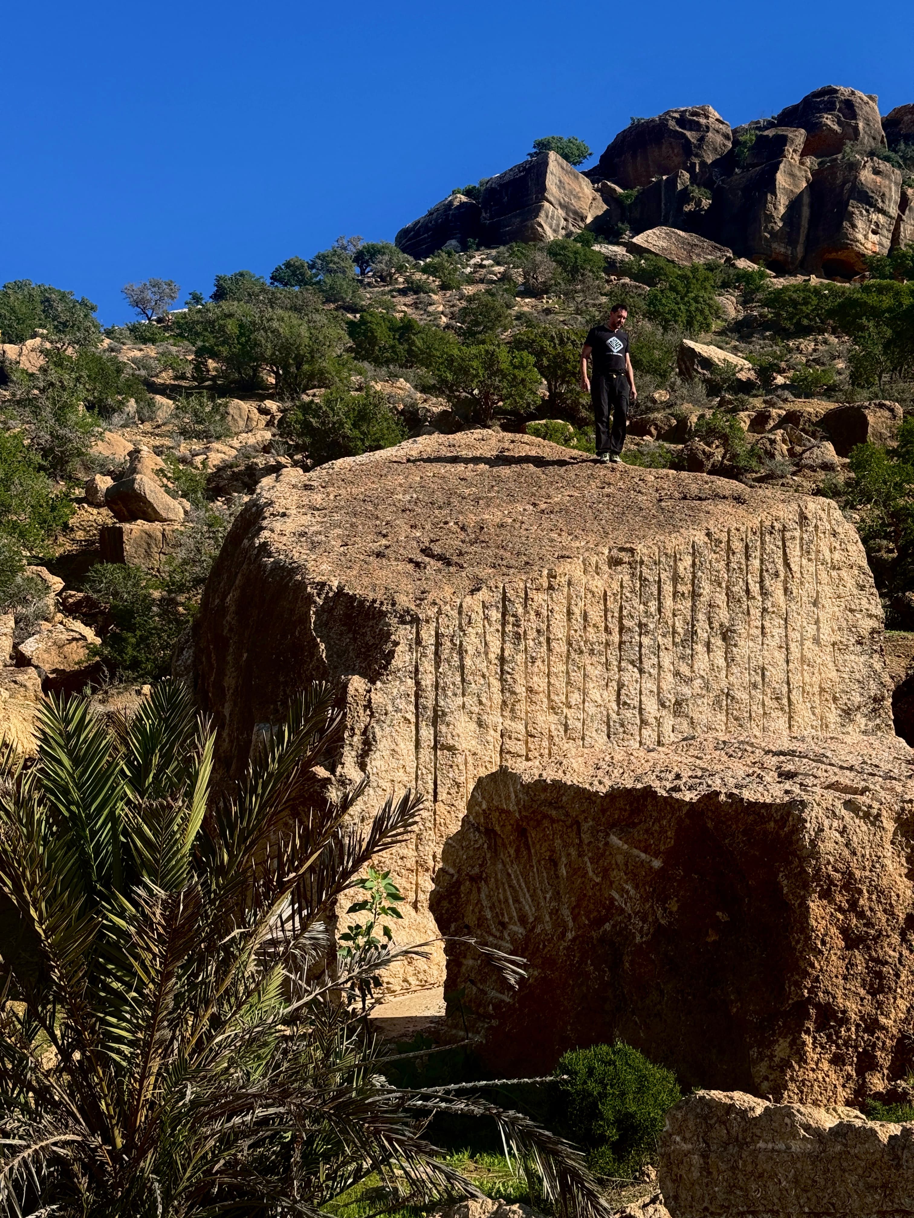A hiker standing atop a large rock formation in the Moroccan mountains